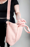 A woman holds the straps of a pink shearling zippered tote bag by Fleece Chic.