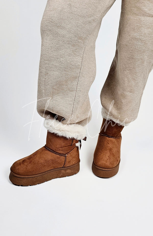 A person wears a pair of winter boots that're brown with a pair of knit pants by Fleece Chic.