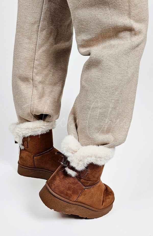 A person wears a pair of winter boots with a fur trim paired with knit pants by Fleece Chic.