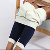 Cozy leggings with a fleece lining that are navy colored are worn by a woman with a gold metallic skirt on who is sitting down - Fleece Chic