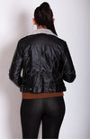 A woman faces away from the camera while wearing a black Vegan Leather Jacket by Fleece Chic.