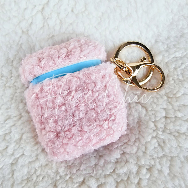 A teddy AirPod Case Cover that is light pink with a golden-colored keychain accent by Fleece Chic.