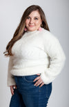 A woman poses in a soft sweater that is white with pink long drop earrings by Fleece Chic.