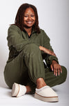 A woman in a green fleece suit wears a pair of white teddy platform slippers by Fleece Chic.