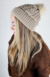 A woman with blonde hair wears Fleece Chic's beige Fleece Beanie paired with a brown sweater.