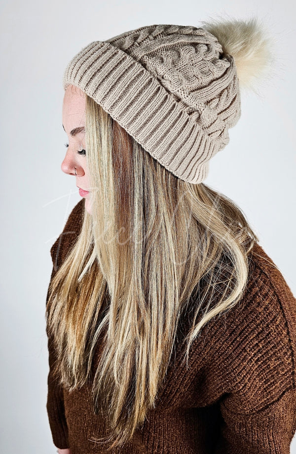 A woman with blonde hair wears Fleece Chic's beige Fleece Beanie paired with a brown sweater.