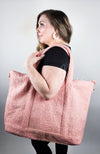 A woman with a zippered tote bag that is pink and made of shearling teddy material by Fleece Chic.
