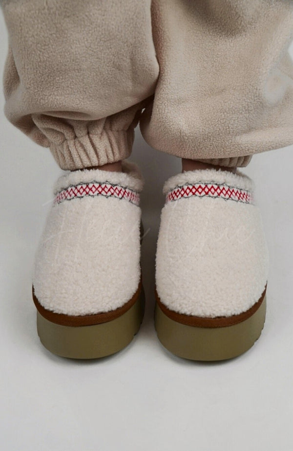 A person wears Curly Tasman Platform Slippers paired with a fleece suit by Fleece Chic.