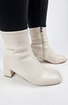 Leather Winter Boots that are cream-colored are worn by a woman in black leggings and have their sides displayed - Fleece Chic