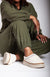 A person wearing white platform slippers with a plush exterior and cozy fleece lining, paired with a green fleece suit by Fleece Chic.