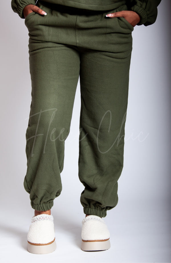 A woman in a green fleece suit wears a pair of white teddy platform slippers by Fleece Chic.
