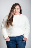 A woman poses in a soft sweater that is white with pink long drop earrings by Fleece Chic.