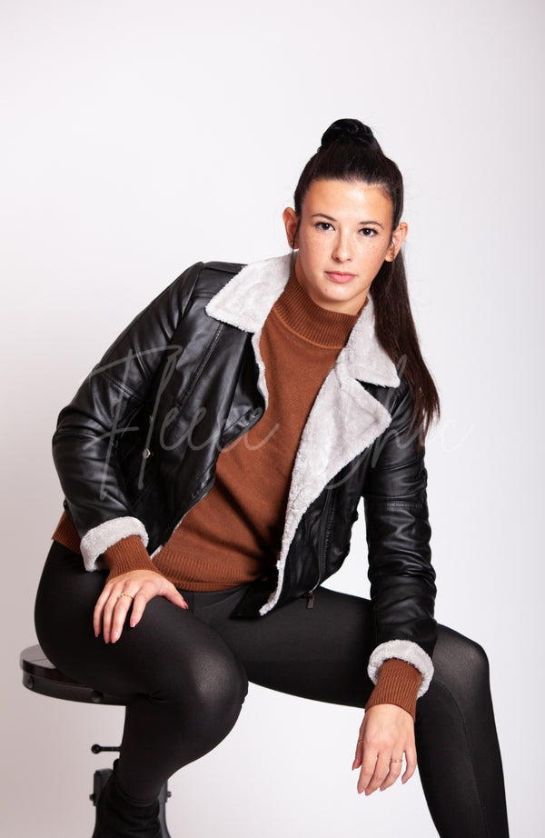 A woman poses on a stool while wearing a Vegan Leather Jacket and a lined Cotton Sweater by Fleece Chic.