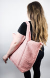 A woman in all black stands facing away from the camera while a zippered tote bag hangs on her shoulder - Fleece Chic