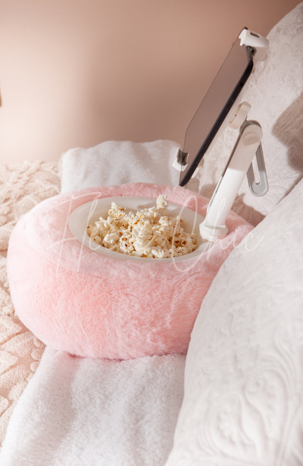 A side profile view of a Tablet Pillow Stand holding popcorn and a Kindle while resting on a bed - Fleece Chic