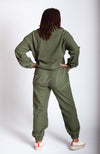A woman in a green fleece suit wears a pair of white teddy platform slippers by Fleece Chic and displays the backside of her outfit.