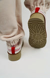 A person wears Curly Tasman Platform Slippers paired with a fleece suit by Fleece Chic and displays their rear and underside.