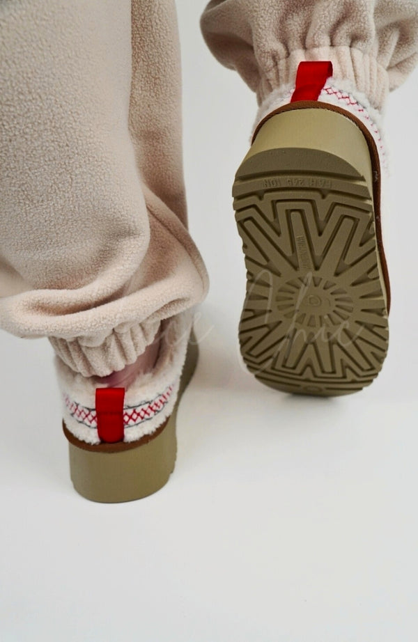A person wears Curly Tasman Platform Slippers paired with a fleece suit by Fleece Chic and displays their rear and underside.