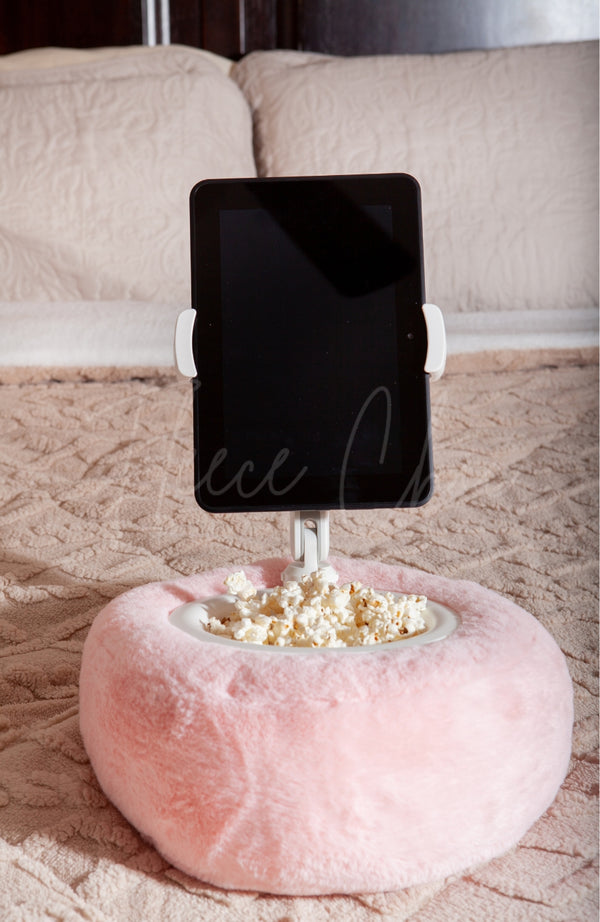 A Tablet Pillow Stand in light pink sitting on a bed holding a Kindle and popcorn in its bowl - Fleece Chic