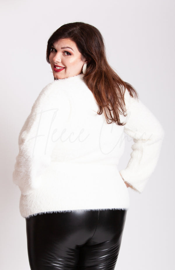 A woman looks over her shoulder at the camera while wearing a crew neck sweater, thermal leather leggings, and plush hoop earrings by Fleece Chic.