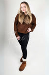 A woman with blonde hair poses in a pair of winter boots, black leggings, and a brown sweater - Fleece Chic