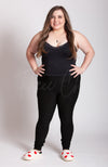 A woman in black clothing wears fuzzy white slippers with red hearts on them - Fleece Chic
