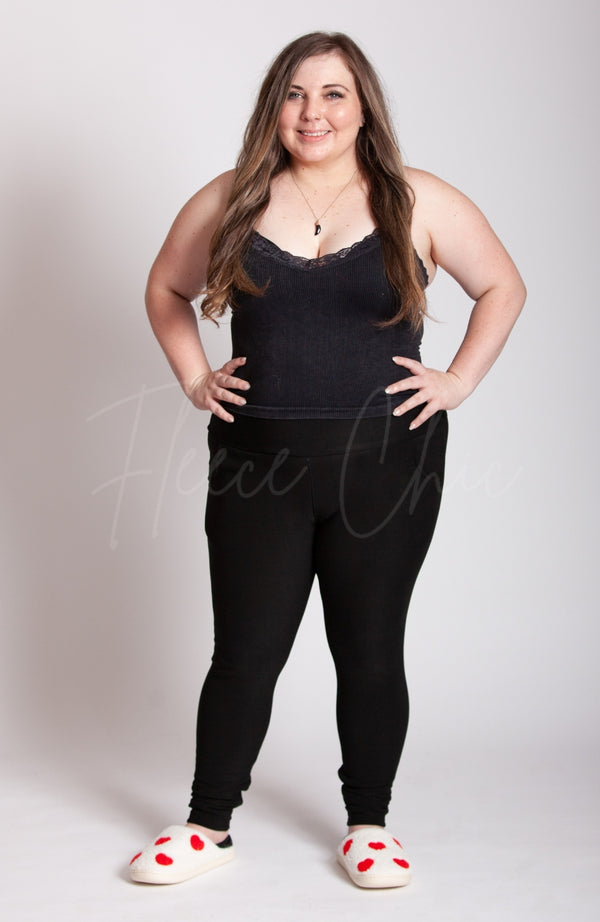 A woman in black clothing wears fuzzy white slippers with red hearts on them - Fleece Chic