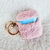 A teddy AirPod Case Cover that is light pink with a golden-colored keychain accent by Fleece Chic on a sherpa background.
