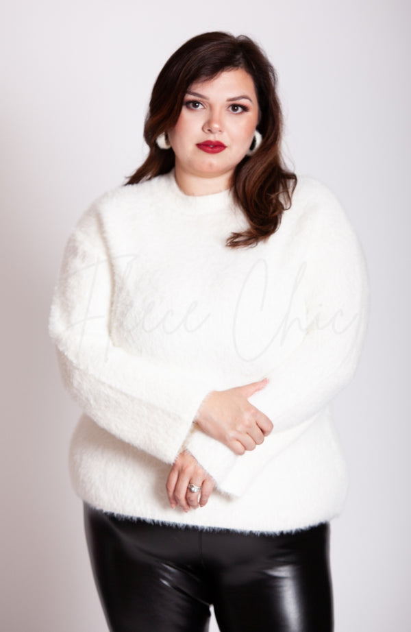 A woman wears a crew neck sweater that is white by Fleece Chic.