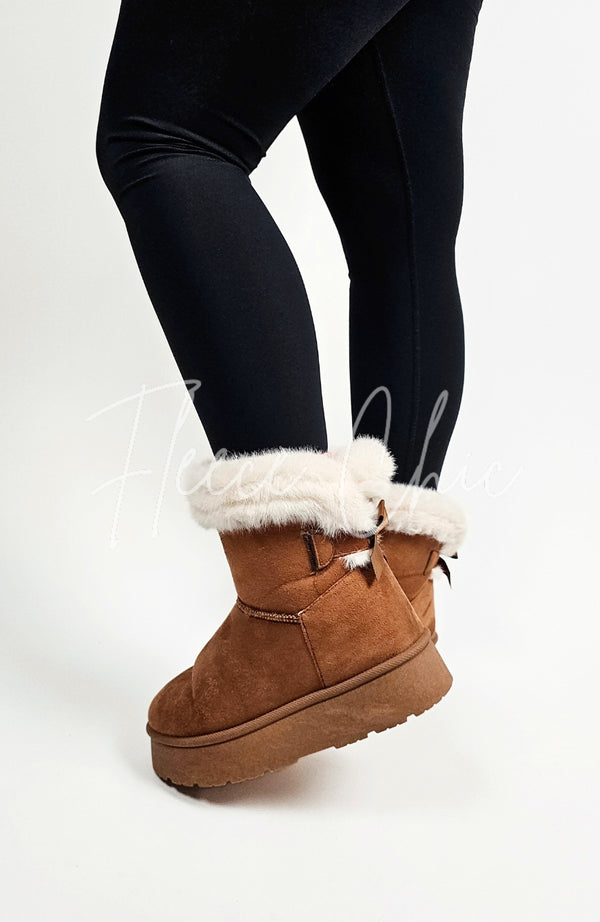 Winter boots with a back bow and fur trim are worn with a pair of black leggings - Fleece Chic