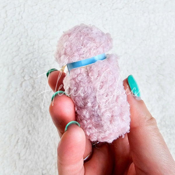 A woman holds up a plush pink AirPod Case Cover with a golden-colored keychain accent, showing its side view - Fleece Chic