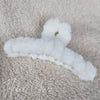 A close-up of a white fluffy claw hair clip by Fleece Chic.