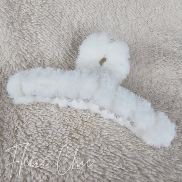 A close-up of a white fluffy claw hair clip by Fleece Chic.