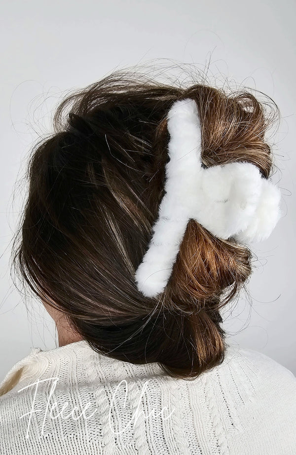 A claw hair clip that is fluffy and white is used to pull back a woman's brown hair in a loose twisted updo - Fleece Chic
