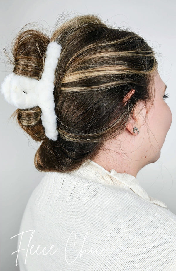 A claw hair clip that is fluffy and white is used to pull back a woman's brown hair in a loose twisted updo - Fleece Chic