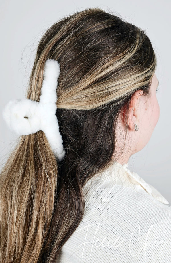 A claw hair clip that is made of white plush is used to pull back a woman's brown hair - Fleece Chic