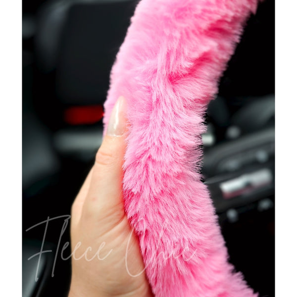A close-up detail shot of a pink steering wheel that is for sale by Fleece Chic.