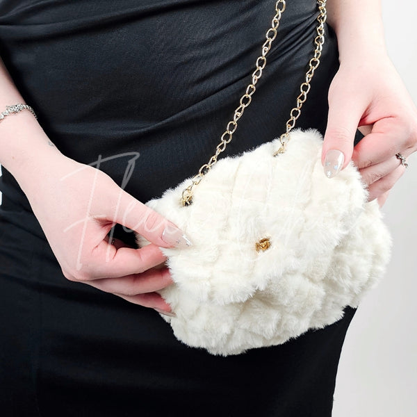 A woman in a black dress poses with a fur purse that is white with diamond patterns on it and a golden chain - Fleece Chic