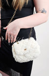 A fur purse that is white is worn by a woman in a black dress - Fleece Chic