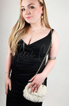 A woman in a black dress poses with a fur purse that is slung over one shoulder - Fleece Chic