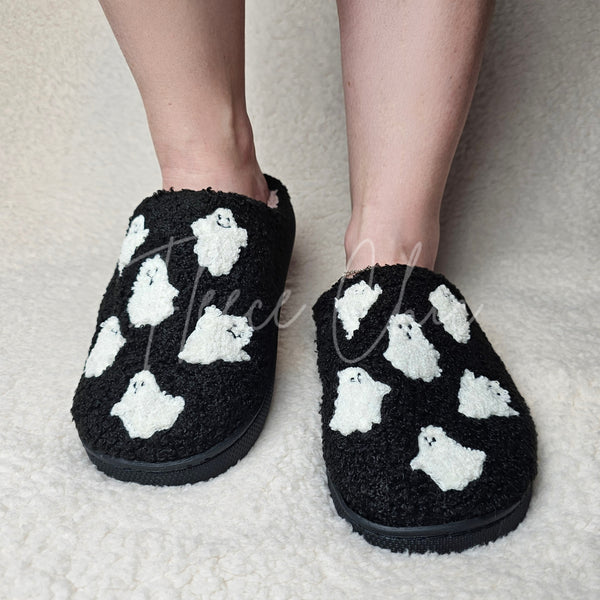 A woman wears fuzzy slippers that are black with white ghosts - Fleece Chic