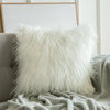 A white Mongolian sheep pillow cover with a hidden zipper, placed on a couch with a grey blanket and a modern chair in the background - Fleece Chic