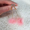 A close up detail shot of a pair of drop earrings that are bright pink by Fleece Chic.