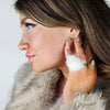 Drop earrings that are fluffy and white are paired with a fox coat by Fleece Chic.