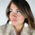 A woman wears a white pair of drop earrings with a fox coat - Fleece Chic