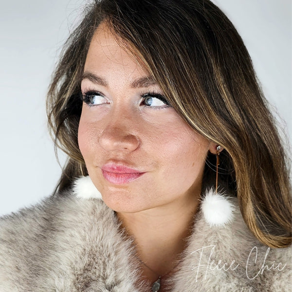 A woman wears a white pair of drop earrings with a fox coat - Fleece Chic