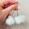 A close up detail shot of a pair of white drop earrings by Fleece Chic.