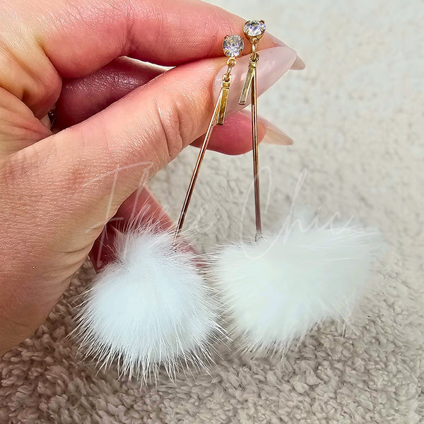 A close up detail shot of a pair of white drop earrings by Fleece Chic.