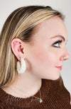 Medium hoop earrings that are white and fluffy are worn by a girl with a brown sweater on - Fleece Chic