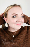 Medium hoop earrings that are white and fluffy are worn by a girl with a brown sweater on - Fleece Chic